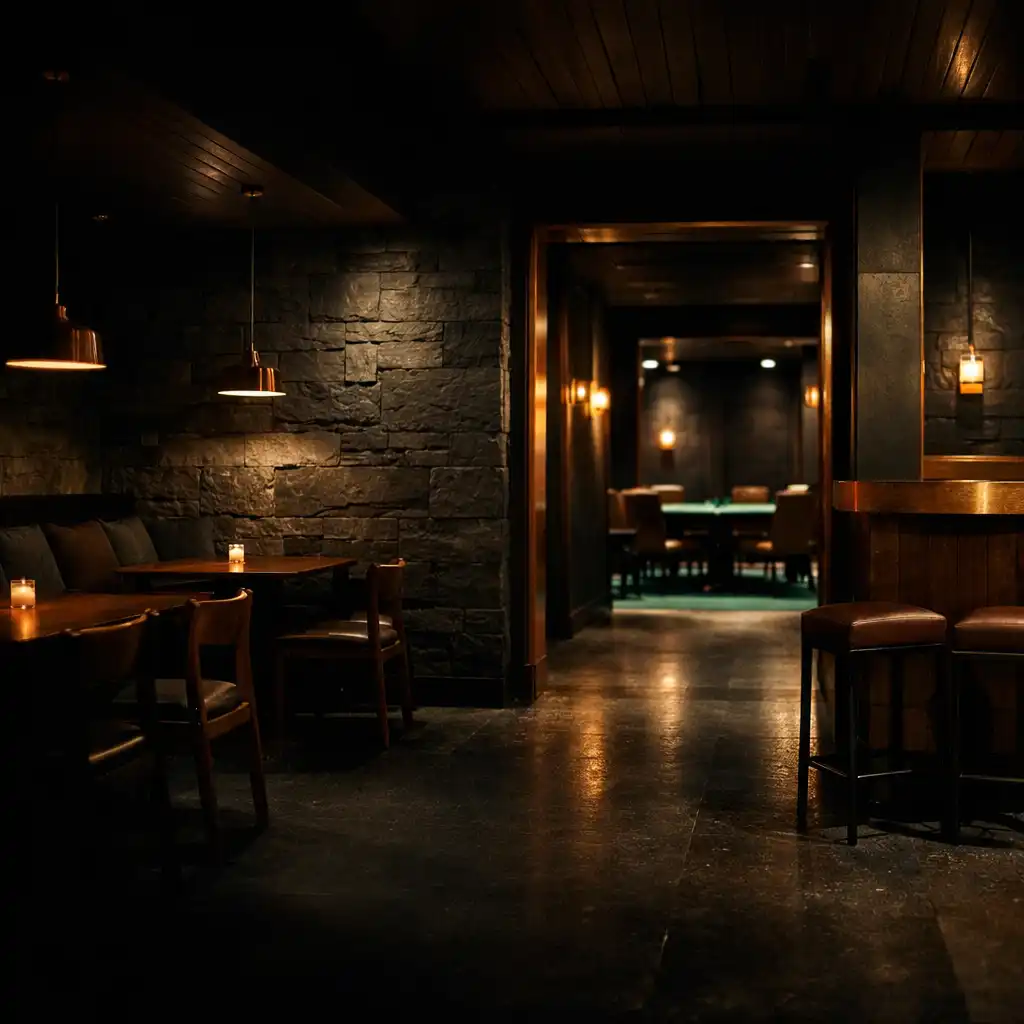 Warmly lit dark bistro interior with slate textures, timber seating and a glimpse of emerald felt